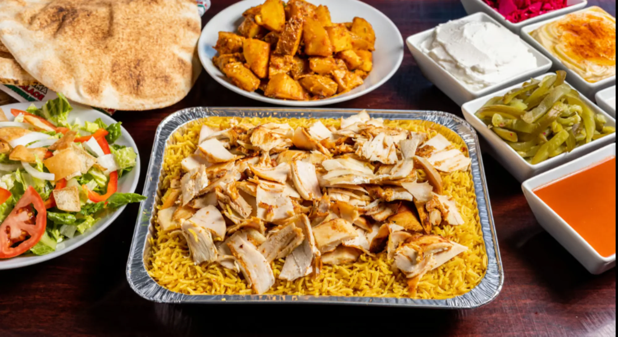 Family Special catering spread with biryani rice, chicken shawarma, salad, potatoes and sauces